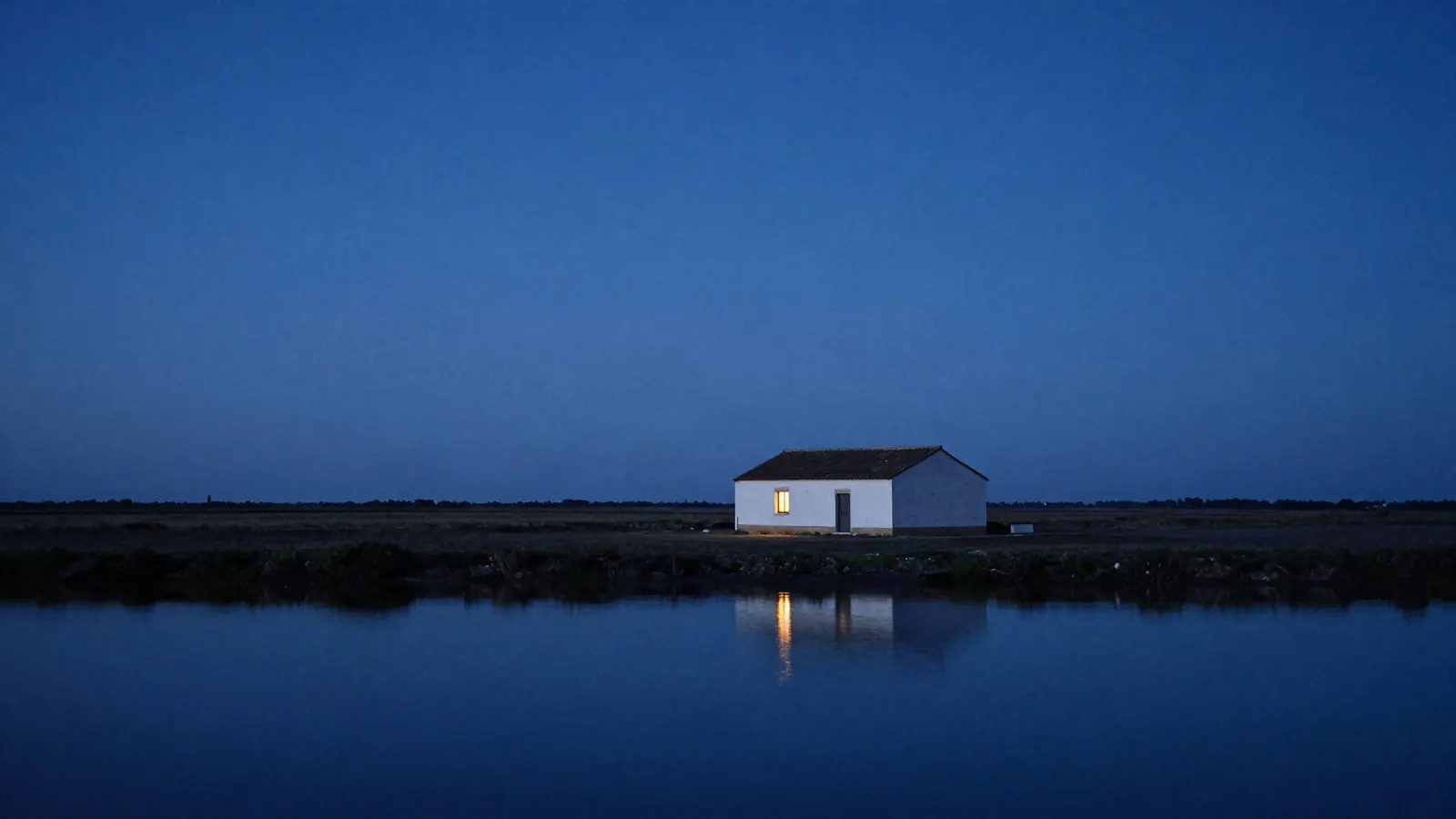 Le mas la nuit, une fenêtre éclairée au-dessus de l'étang